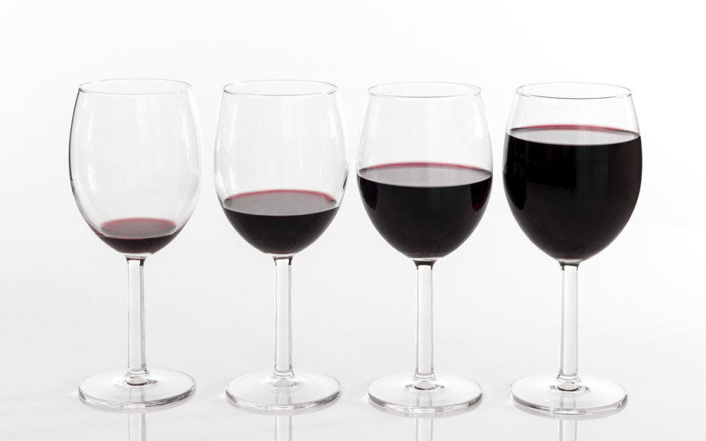 Four glasses filled with different quantities of red wine.